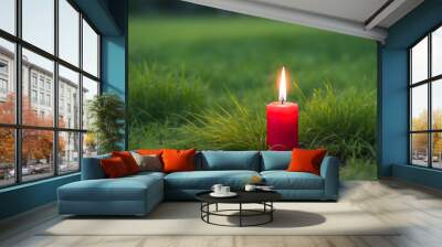 Red candle on green grass, blurred grass background Wall mural