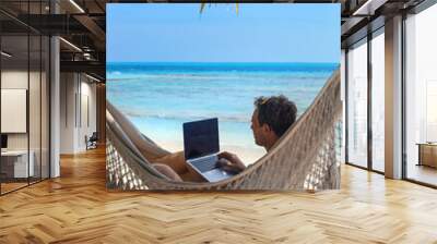 digital nomad, man working on laptop from hammock on the beach, dream job Wall mural