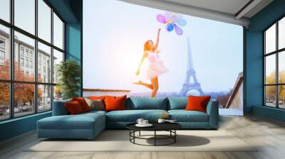 dream travel, girl with balloons jumping near Eiffel Tower in Paris Wall mural