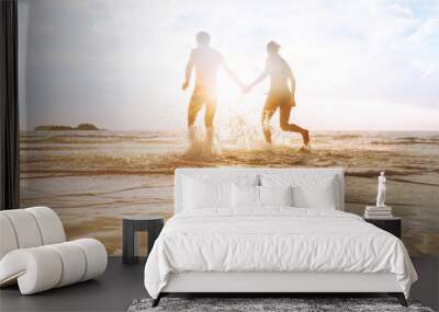 happy young couple having fun on the beach at sunset, water splash, enjoying life Wall mural