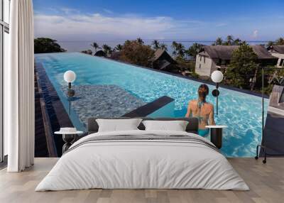 luxury vacation, woman entering rooftop infinity pool in luxurious hotel resort Wall mural