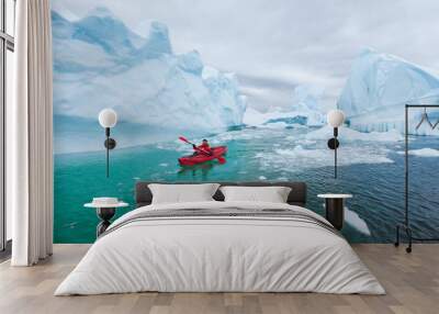 man paddling on kayak between ice in Antractica in Iceberg Graveyard, extreme winter kayaking, polar adventure near Pleneau island Wall mural