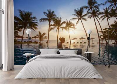 spa, silhouette of woman relaxing near swimming pool on the beach at sunset in luxury hotel Wall mural