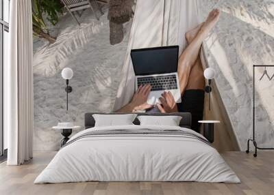 workation, remote work, freelancer with laptop in hammock on tropical beach Wall mural