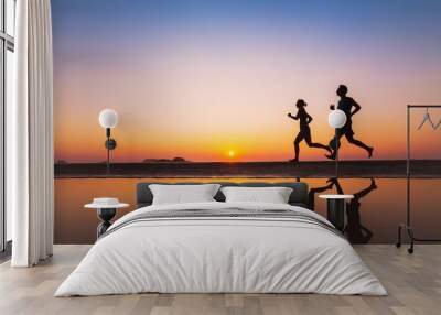 workout, silhouettes of two runners on the beach at sunset, sport and healthy lifestyle background Wall mural