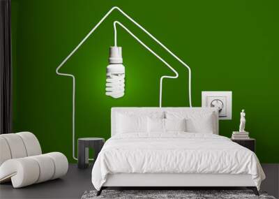 Glowing lightbulb in a house on a green background Wall mural