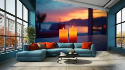   Two candles rest on a table near a window overlooking distant water Wall mural