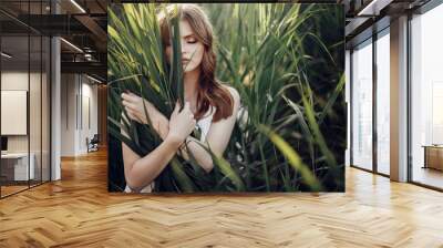 beautiful boho girl posing in grass at sunset light near lake. attractive sensual young woman embracing in cane near beach. summer vacation. save environment concept Wall mural