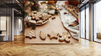 Christmas gingerbread cookies on vintage plate and anise, cinnamon, pine cones, cedar branches  with golden lights on rustic table. Baked traditional gingerbread man, tree, star cookies Wall mural