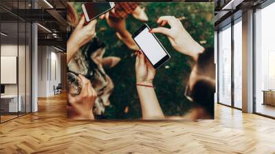 empty phone screen in woman hands with space for text. young girl holding smartphone and pointing at party celebration, looking at screen and drinking champagne Wall mural