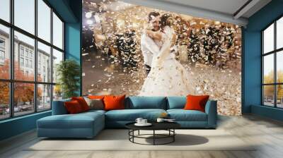 Gorgeous bride and stylish groom dancing under golden confetti at wedding reception. Happy wedding couple performing first dance in restaurant. Romantic moments Wall mural