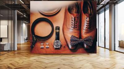 Stylish watch, expensive, shoes, bow tie, cufflinks and belt for groom on wooden table in hotel room. Morning preparation before wedding ceremony. Men accessory for luxury event Wall mural