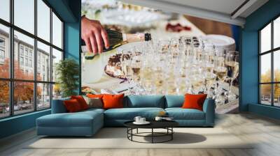 waiter pouring champagne in stylish glasses at luxury wedding reception. rich celebration. expensive catering and service at feast. new year and christmas celebrations and drinks Wall mural