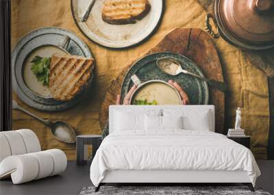 Autumn, Winter home dinner. Flat-lay of Fall warming celery cream soup in cups, grilled bread and female hands over linen tablecloth, top view. Comfort food, vegetarian, healthy and slow food concept Wall mural