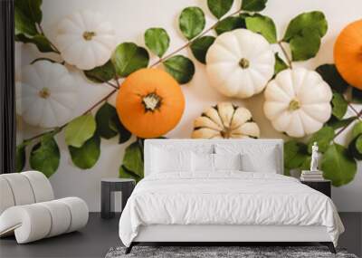 Autumn floral layout. Flat-lay of colorful Fall pumpkins and green leaves over plain white background, top view, wide composition. Halloween, Thanksgiving or Autumn table decoration concept Wall mural