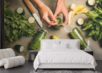 Making green detox smoothie. Flat-lay of ingredients for making smoothie and female hands holding bottle with straw over concrete background, top view. Weight loss, healthy food concept Wall mural