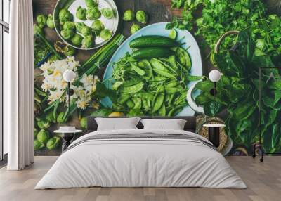 Spring healthy vegan food cooking ingredients. Flat-lay of vegetables, fruit, seeds, sprouts, flowers, greens over wooden background, top view, wide composition. Diet, clean eating food concept Wall mural