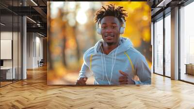 Happy black man jogging in the park while listening to music through his headphones. Candid male running for improved mental health and fitness. Autumn colours. AI generated Wall mural