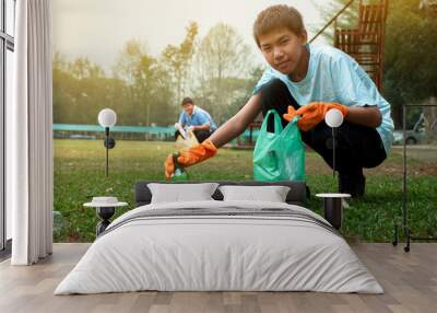 Asian boy in caucasian is clearing and separating garbages with his friend at the park, soft and selective focus, environment care, community service and summer vacation activity of teenagers concept. Wall mural