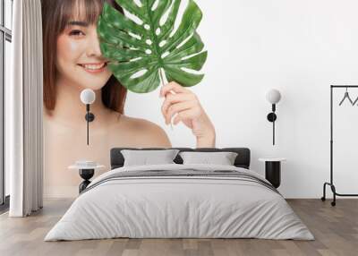 Beauty asian woman  brown hair looking smile in camera happiness and holds a large green tropical leaf in hands and covers a part of her face and cheerful with make up brush,Beauty Concept. Wall mural