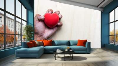 red  pillow heart in hand with on wood table Wall mural