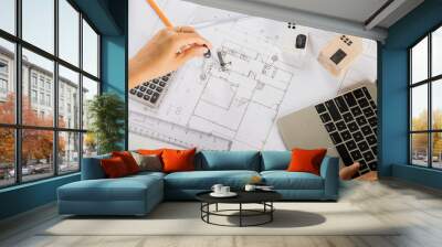 Architectural project workplace. Architect typing laptop keyboard to review design of house before editing or sketching with compass on plan blueprint paper on table desk at architecture office Wall mural