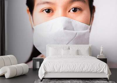 Asian beautiful woman wearing protection face mask against coronavirus her looking to camera, studio shot isolated on white background with copy space, COVID-19 or corona virus concept Wall mural