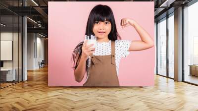 Asian little kid 10 years old smile holding milk glass and show power strong gesture at studio shot isolated on pink background, Portrait of Happy child girl daily life health care medicine food Wall mural