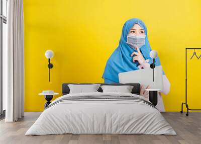 Asian Muslim Arab, Portrait of happy beautiful young woman Islam religious wear veil hijab and face mask protect she quarantines disease coronavirus hold laptop computer and thinking question Wall mural