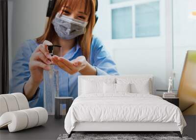 Asian young business woman wearing face mask protective working from home office with laptop computer he quarantines disease coronavirus or COVID-19 and cleaning hands with sanitizer alcohol gel pump Wall mural