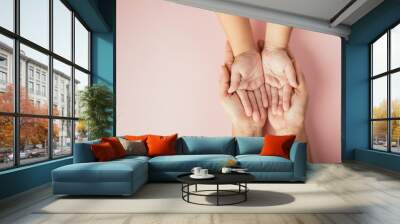 Close up hands children on adult mother hand, Top view person kid stack mom palms, Parents and little kid holding empty hands together isolated on pink background, Family day care concept Wall mural