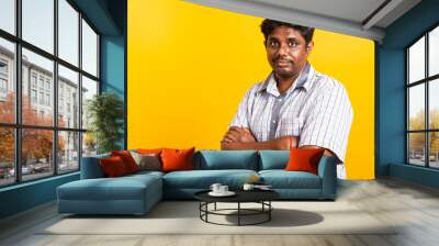 Closeup Asian happy portrait young black man standing cross arms chest confident pose and looking camera, studio shot isolated on yellow background Wall mural