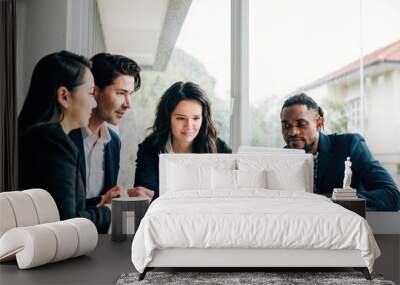 Diverse group of men and women in business collaborates in meeting room use laptop. Their teamwork diversity and cooperation are evident they engage in discussion planning and strategizing for success Wall mural