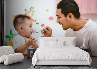 Father acting Mom feeding his son baby 1 year old on chair Wall mural