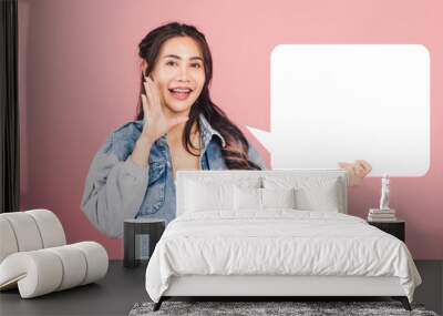 Happy Asian beautiful young woman smiling excited wear denims hand near mouth announce news and holding empty speech bubble sign, Portrait female posing idea, studio shot isolated on pink background Wall mural