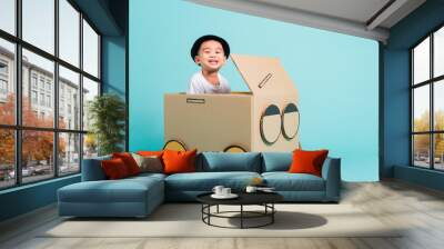 Happy Asian children boy smile in driving play car creative by a cardboard box imagination, summer holiday travel concept, studio shot on blue background with copy space for text Wall mural