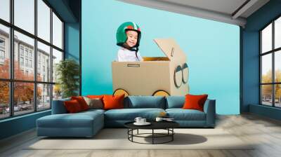 Happy Asian children boy with Helmet smile in driving play car creative by a cardboard box imagination, summer holiday travel concept, studio shot on blue background with copy space for text Wall mural