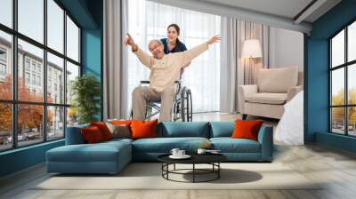 Happy curator person doctor pushing wheelchair and run elderly disabled patient freedom raising arm at hospital, senior retired man sitting on wheelchair having fun with young woman nurse, health care Wall mural