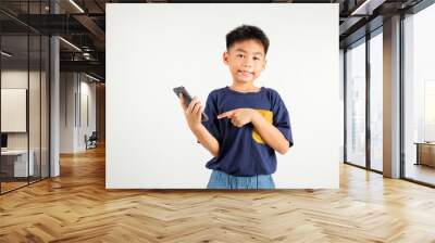 Portrait Asian happy young kid boy smile making finger pointing on screen smartphone in hand, Primary children attractive shopping online application isolated studio shot white background Wall mural