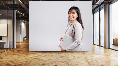 Side view woman smiling confident smiling holding closed laptop, Portrait excited happy Asian young female person hugging close cover computer device studio shot isolated on white background Wall mural