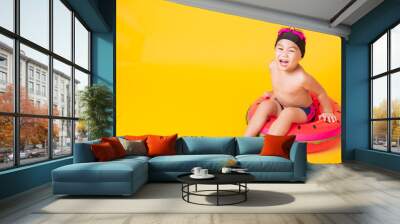 Summer vacation concept, Portrait Asian happy cute little child boy wear goggles, swimsuit hold beach watermelon inflatable ring, Kid have fun sit in inflatable, studio shot isolated yellow background Wall mural