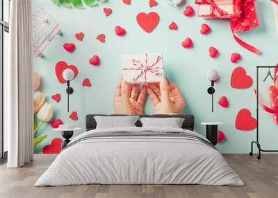 Valentine's day and birthday. Woman hands holding gift or present box decorated and red heart surprise on blue background, Female's hand hold gift box package in craft paper Top view flat lay Wall mural