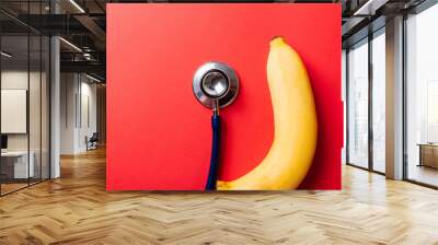 World sexual health or Aids day, Top view flat lay of doctor stethoscope and yellow banana, studio shot isolated on a pink background, Safe sex and reproductive health concept Wall mural