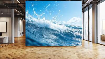 A vibrant ocean wave splashing under a clear blue sky, capturing the beauty and energy of nature's water dynamics. Wall mural