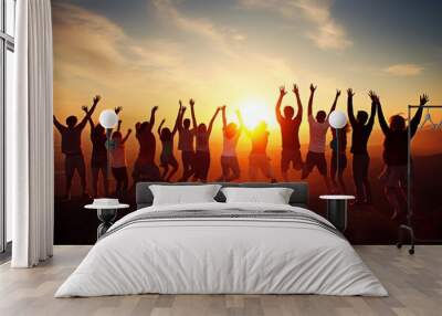 Silhouetted group of people jumping in front of bright sunrise over mountain peaks Wall mural