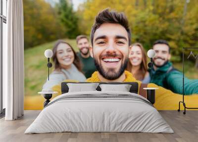 Cheerful group of friends taking a selfie outdoors in autumn, showcasing joy and connection amidst beautiful seasonal colors. Wall mural