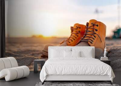 Pair of brown leather boots on a sandy beach at sunset. Wall mural