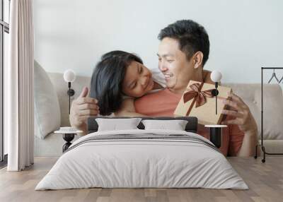 asian father giving gift box for daughter  in the living room. Cute girl and father sitting on sofa be happy  in home Wall mural