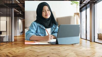 Muslim girl is studying online via  internet on tablet at home morning Wall mural