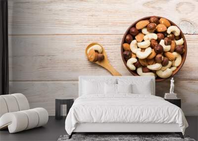 Assortment of nuts in wooden bowl on colored table. Cashew, hazelnuts, walnuts, almonds. Mix of nuts Top view with copy space Wall mural